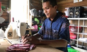 Ahmad Romeli sedang menjahit