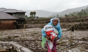 Foto: Seorang warga sedang membawa barang-barang akibat bencana banjir bandang, di Sumatra. Sumber: Istimewa.