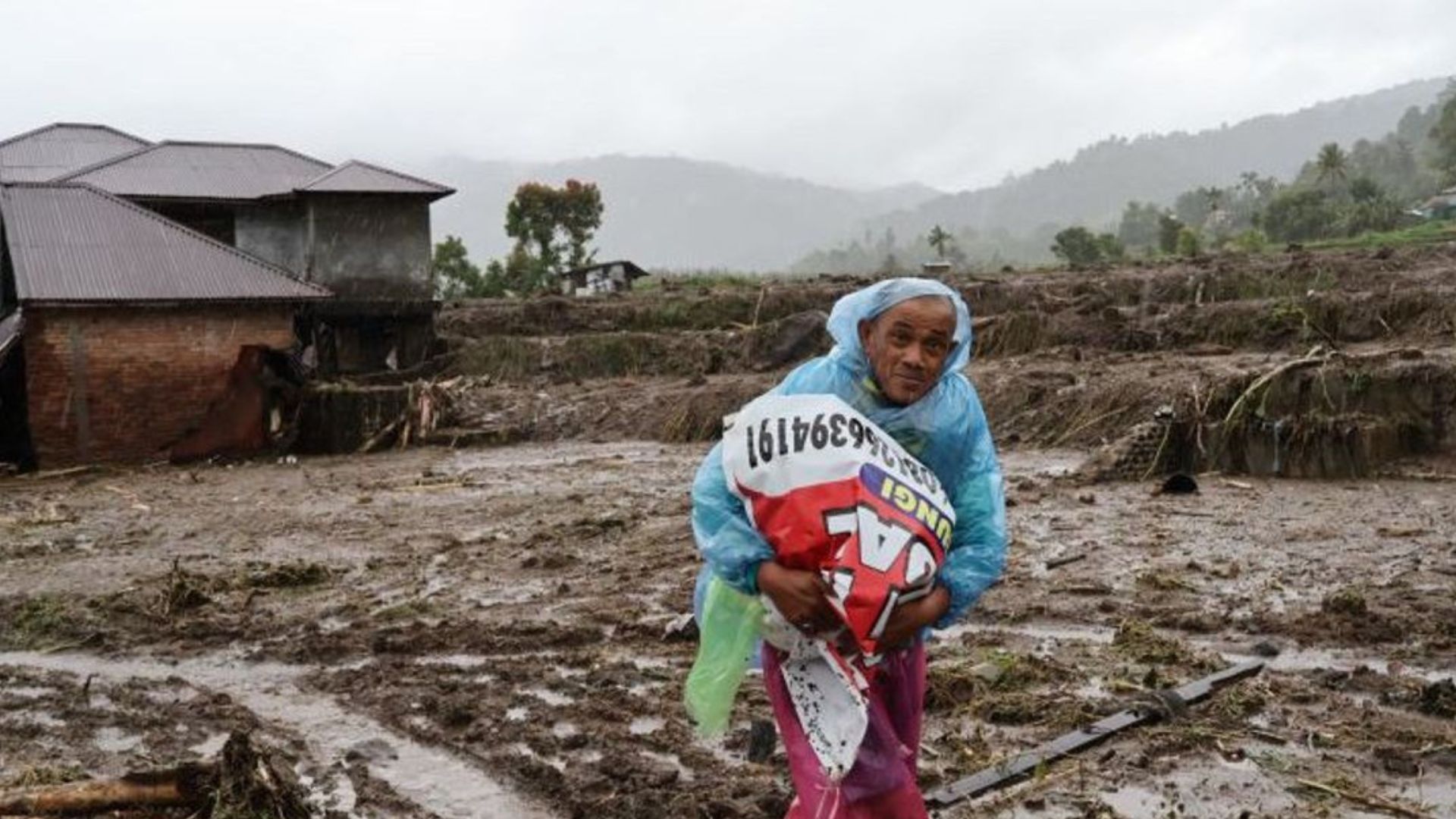 Foto: Seorang warga sedang membawa barang-barang akibat bencana banjir bandang, di Sumatra. Sumber: Istimewa.